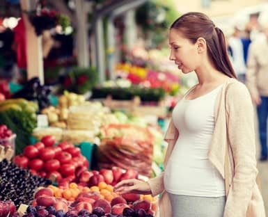 Dieta para quedar embarazada: mujer eligiendo alimentos saludables en el mercado