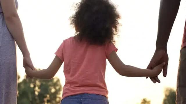 Nina-sosteniendo-la-mano-de-sus-padres-en-la-copaternalidad