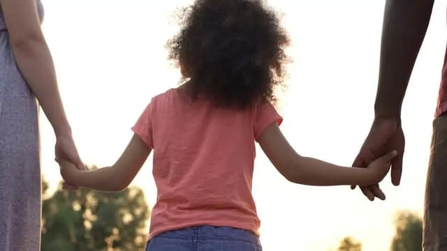 Nina-sosteniendo-la-mano-de-sus-padres-en-la-copaternalidad